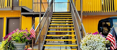 Una escalera conduce a un edificio amarillo con balcones y barandillas.