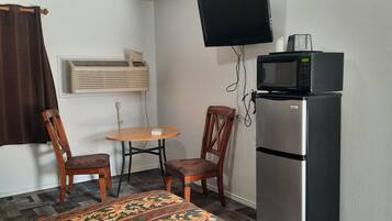 A small kitchenette with a refrigerator, microwave, and a single chair.