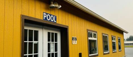 Un bâtiment jaune avec une enseigne indiquant « PISCINE » au-dessus de l’entrée.