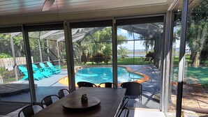 A covered patio with a pool, outdoor seating, and a view of the surrounding landscape.