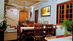 A dining area with wooden furniture, a chandelier, and a painting on the wall. - Casa do Papai Pousada (Campos do Jordão)