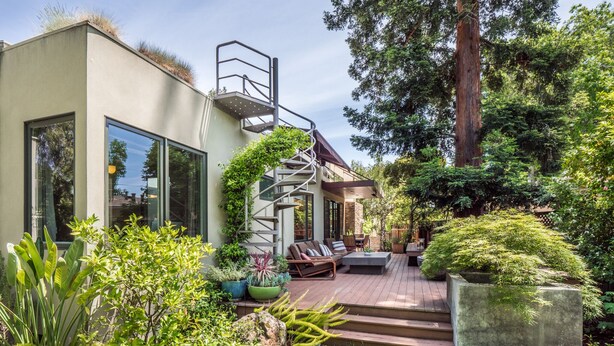 A modern house with a patio, outdoor seating, and a spiral staircase.