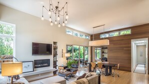 A modern living room with a fireplace, a dining area, and a kitchen.