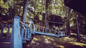 Une terrasse en bois menant à un chalet situé dans une forêt.