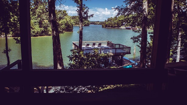 Une terrasse au bord du lac, avec une table et des chaises, entourée d’arbres et offrant une vue sur un lac paisible.