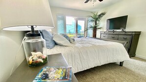 A bedroom with a bed, a nightstand, a lamp, a TV, and a window with blinds. - Rockport(Little Palm@ Key Allegro)Waterfront Beautiful Condo Close to Everything (Rockport)