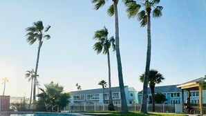 A swimming pool surrounded by palm trees and a hotel building with multiple balconies. - Rockport(Little Palm@ Key Allegro)Waterfront Beautiful Condo Close to Everything (Rockport)