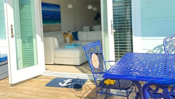 An open door leading to a living area with a sofa, a table, and chairs. - Rockport(Little Palm@ Key Allegro)Waterfront Beautiful Condo Close to Everything (Rockport)