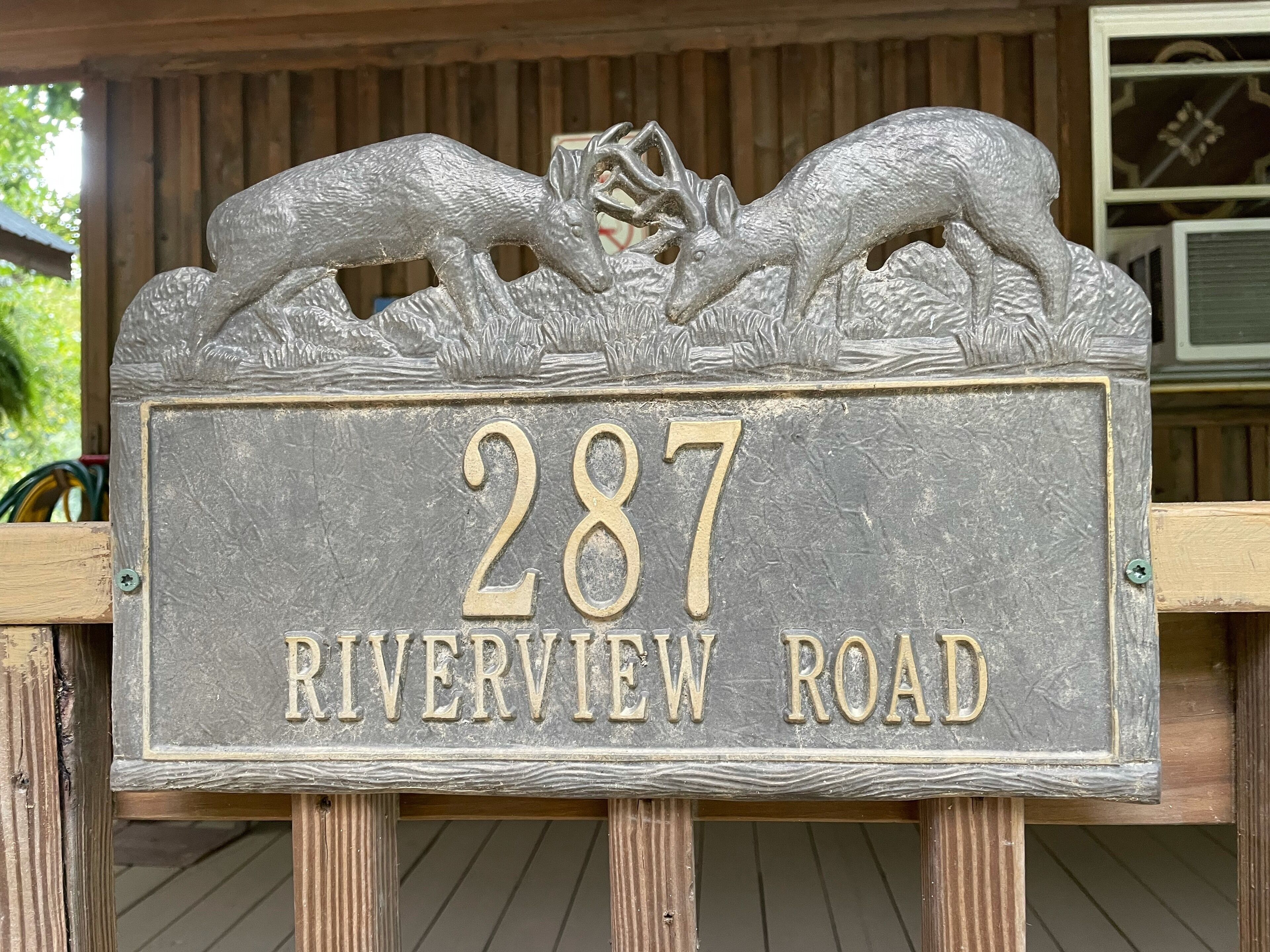 Une plaque de numéro de maison avec deux figurines de cerfs au-dessus du numéro 287 et l’inscription « Riverview Road ».