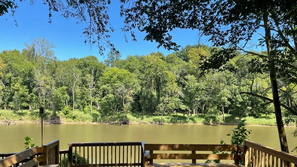 A wooden deck with benches overlooking a calm lake surrounded by dense trees.