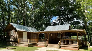 A rustic cabin with a metal roof, wooden deck, and a covered porch.