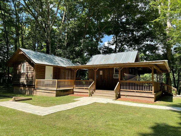 A rustic cabin with a metal roof, wooden deck, and a covered porch.