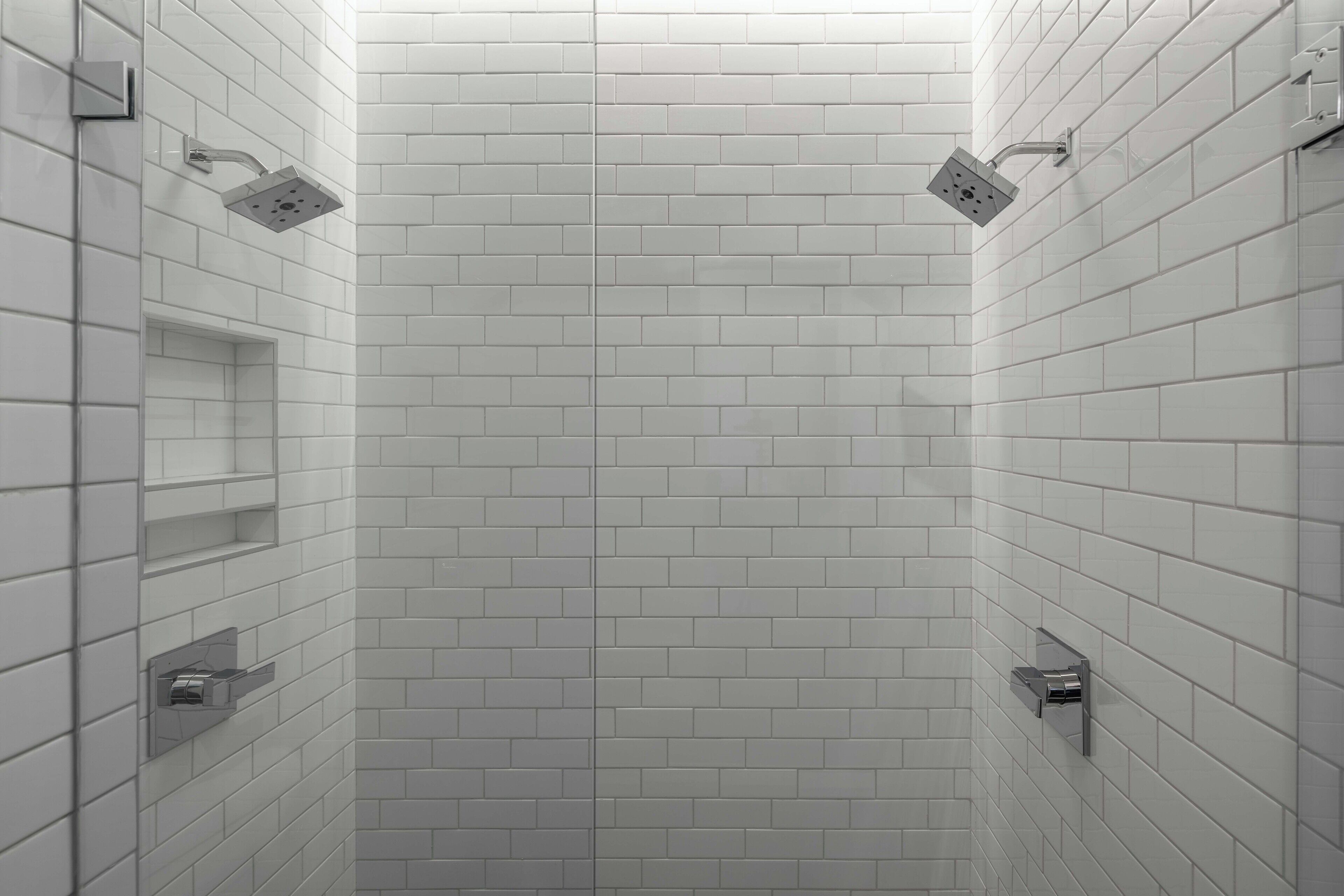 A modern bathroom with white subway tiles, a showerhead, and a towel rack.
