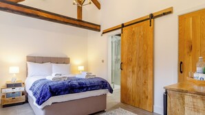 A bedroom with a bed, bedside lamps, a wooden wardrobe, and a shower.