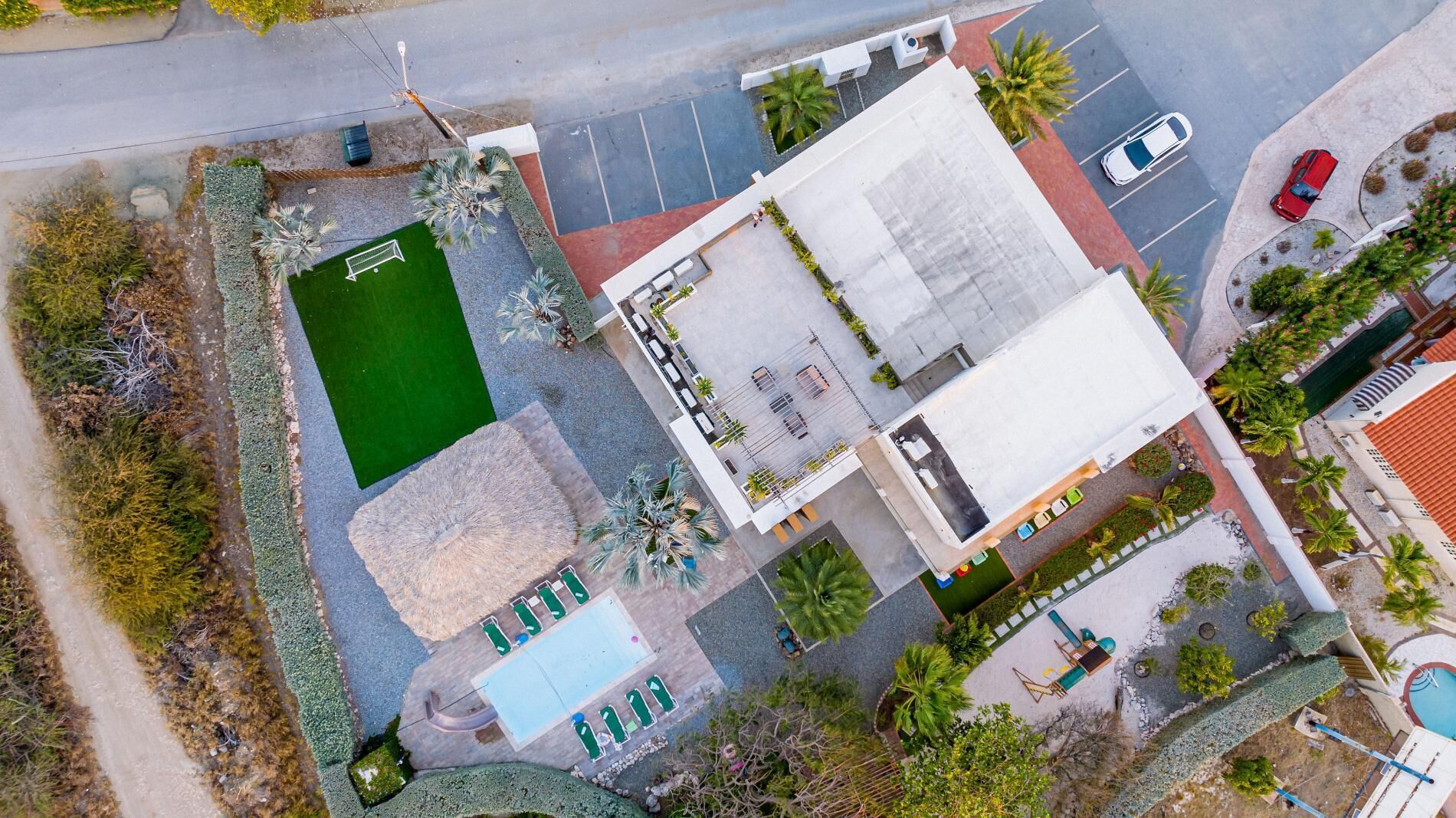 An aerial view of a hotel with a swimming pool, outdoor seating area, and a parking lot.