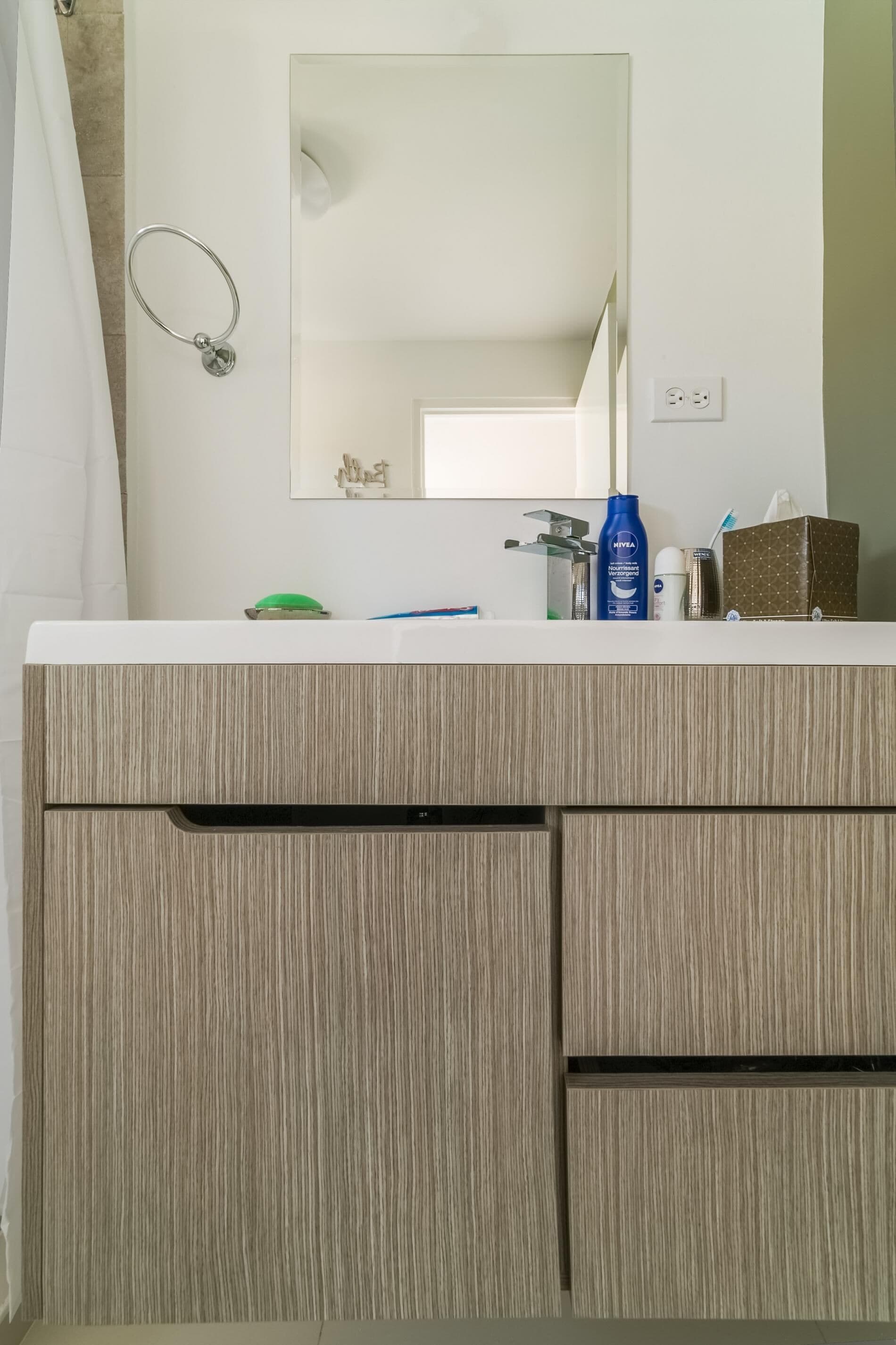 Une salle de bain avec un meuble-lavabo en bois, un miroir et des articles de toilette.