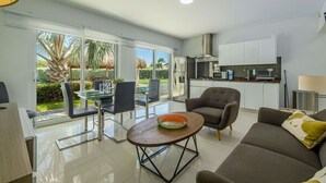Un salon moderne comprenant un canapé, une table basse et un coin repas avec des chaises et une table en verre.