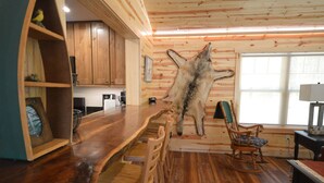Un interior rústico con paredes de madera, una barra de madera y un gran trozo de piel de animal colgado en la pared.