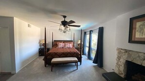 A bedroom with a four-poster bed, a stone fireplace, and a ceiling fan. - Chalet-style Home Perfect for Family - Heated Pool (Simi Valley)