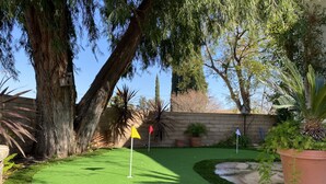 A well-maintained garden with a putting green, a large tree, and various potted plants. - Chalet-style Home Perfect for Family - Heated Pool (Simi Valley)