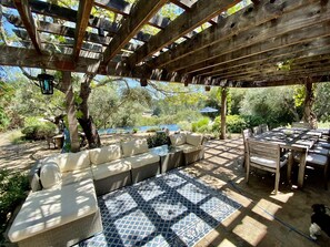 An outdoor patio with a pergola, seating area, and a view of the surrounding garden. - Villa Luba Helena (St Helena)