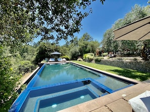 A swimming pool with a stone wall and a lounge area with chairs.