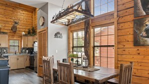 A rustic wooden interior with a dining table, chairs, and a kitchen area.