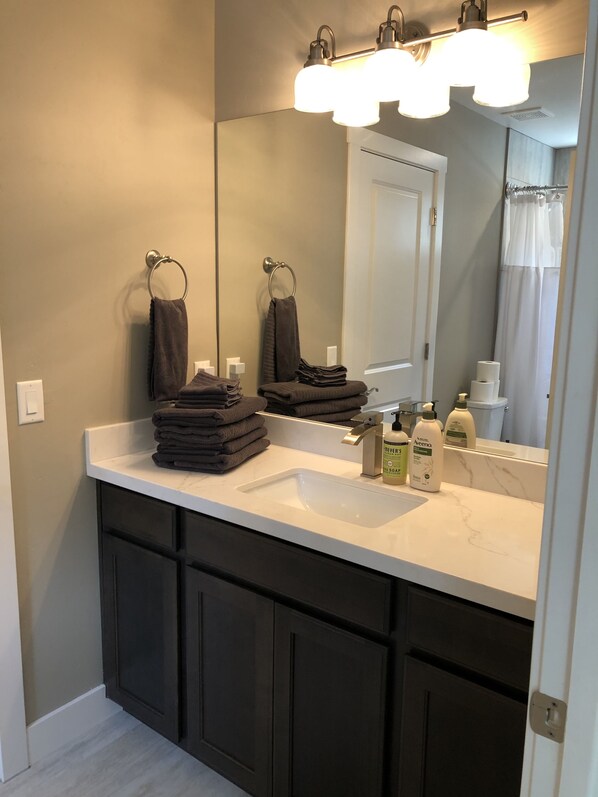 A bathroom with a white sink, dark cabinets, a mirror, and a towel rack.