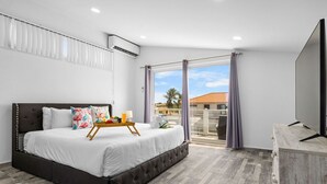 Una camera da letto moderna con un letto grande, una televisione e un balcone con tende.