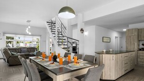 Una cucina moderna con isola centrale, una zona pranzo con una scala e un soggiorno con divano e tavolino.