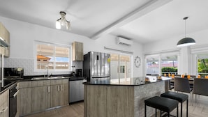 Una cucina moderna con isola centrale, elettrodomestici in acciaio inossidabile e vista sull'esterno.