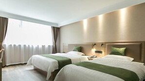 A hotel room with two beds, a bedside table with a lamp, and a window with curtains. - Greentree Inn (Nanjing)