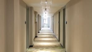 A long, narrow hallway with a carpet featuring a leaf pattern. - Greentree Inn (Nanjing)