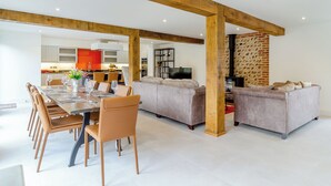 Un amplio espacio de estar con mesa de comedor, sofás y chimenea.