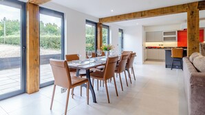 Un comedor moderno con techo de madera, ventanas amplias y vistas a zonas verdes.