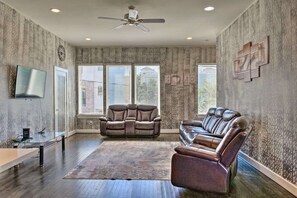 A spacious living room with a large window, a ceiling fan, and a leather sofa.