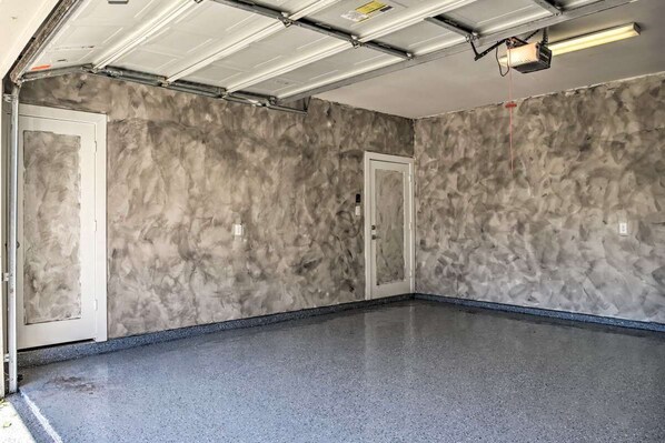 A garage with a concrete floor and walls, a closed garage door, and a ceiling with fluorescent lighting.