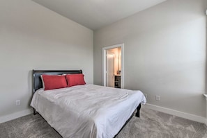 A bedroom with a bed, a door, and a carpeted floor.