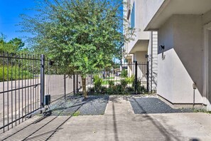 A gated residential area with a tree, a concrete pathway, and a building with a white facade.