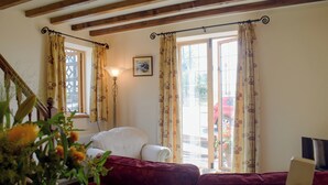 A cozy living room with a wooden ceiling, a red sofa, a wooden table, and a vase with flowers. - 1 bedroom accommodation in Tregynon (Tregynon)