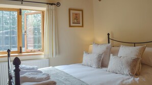 A bedroom with a bed, pillows, a window with curtains, a radiator, and a framed picture on the wall. - 1 bedroom accommodation in Tregynon (Tregynon)