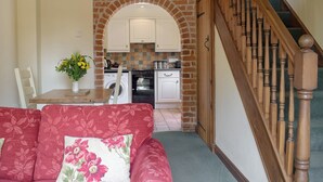 A living room with a red sofa and a wooden staircase. - 1 bedroom accommodation in Tregynon (Tregynon)