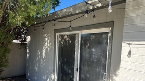 Ein Haus mit einer Schiebetür und einem kleinen Patio mit Kies und Lichterketten.