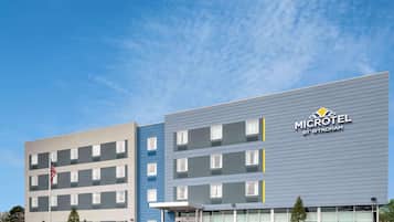 Un micro-hôtel moderne à la façade sobre, doté de nombreuses fenêtres et offrant une vue sur un ciel dégagé.