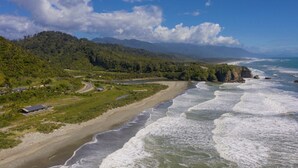 Eine Küstenlandschaft mit Strand, Straße und einem Gebirgszug.
