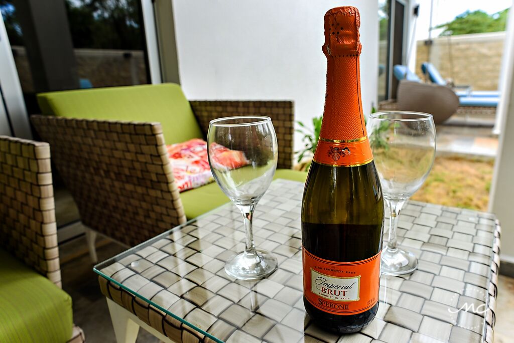 A bottle of Imperial Brut wine on a glass table with two empty wine glasses.