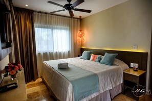 Ein Hotelzimmer mit einem Bett, Vorhängen, einem Deckenventilator, einem Nachttisch und einer Wandleuchte.