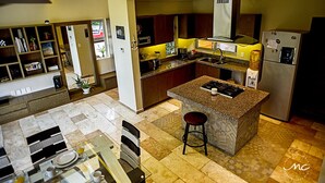 A modern kitchen with granite countertops, a central island, and a dining area with a glass table and chairs.