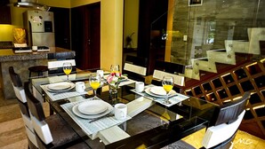 A dining area with a glass table set for four, surrounded by chairs.