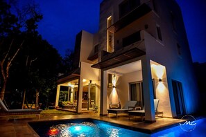 A modern two-story building with a swimming pool, outdoor seating, and a well-lit entrance. - Beautiful 5-Room Villa w/Private Pool in Puerto Morelos — 5 min from the beach! (Puerto Morelos)
